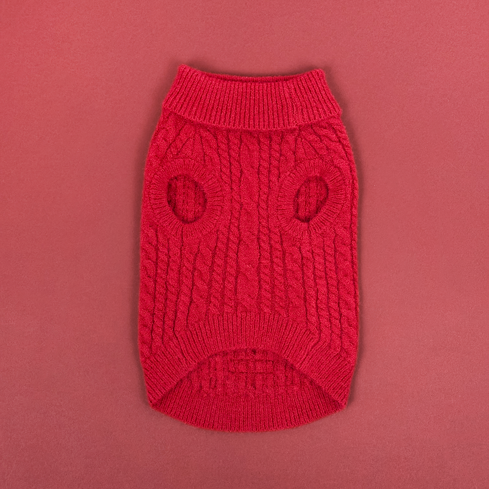 Red cable knit dog jumper with two leg holes, laid flat on a matching red background.