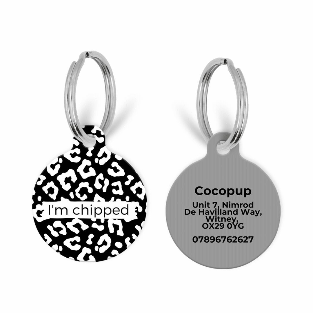 Two Cocopup London dog ID tags, both round: one with leopard print, one white with printed contact info and address.