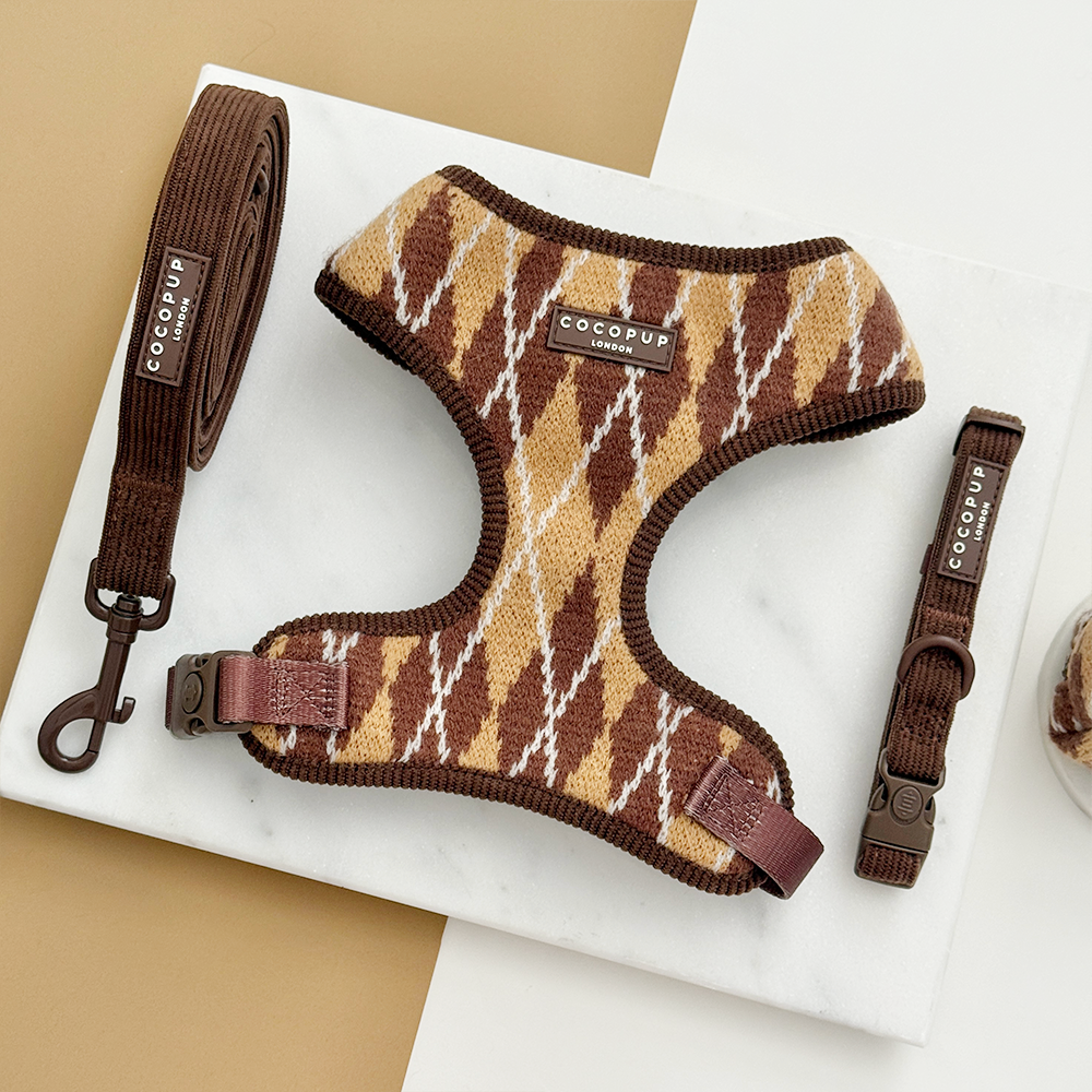 Dog harness, lead and collar with a brown, tan, and white argyle pattern. The lead and collar are a brown ribbed material.