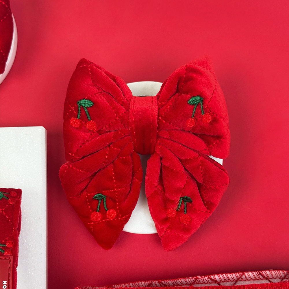 Red bow with cherry details on a red background