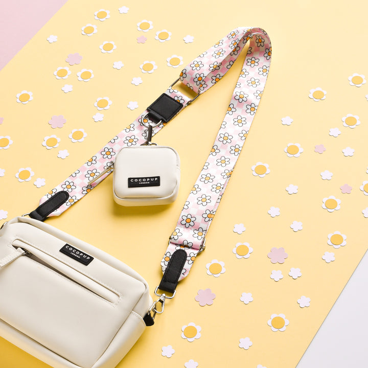 A white bag with the Cocopup London "Daisy Gingham Rave" pink, versatile strap on a yellow background.