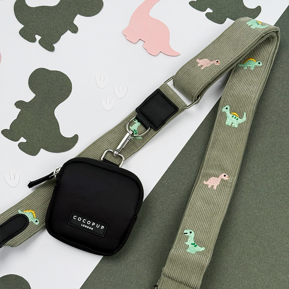 Green corduroy material Bag Strap with embroidered dinosaurs. Attached is a Cocopup London Treat Pouch.