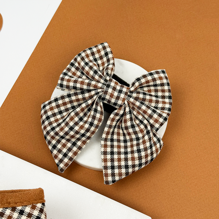 Brown and white checkered sailor bow tie with black accent, displayed on a white dish.