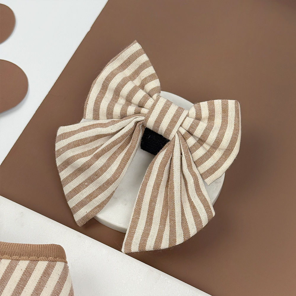 Brown and beige striped dog sailor bow tie on a brown background.