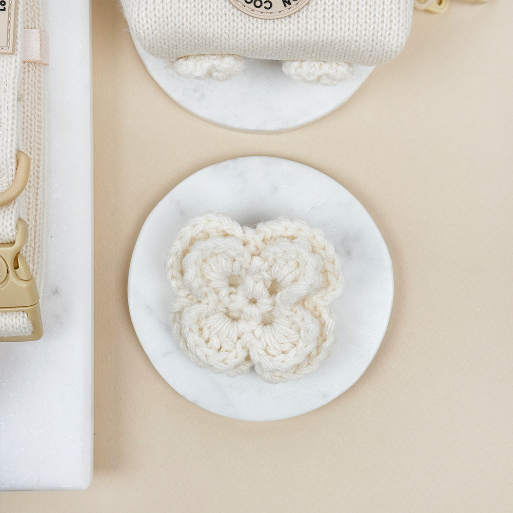 White crocheted Dog Collar Flower on a beige background.