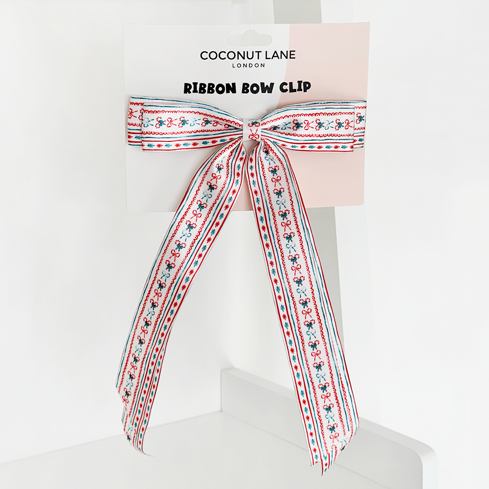 A decorative ribbon bow clip featuring a red, white, and blue floral pattern is showcased against a white background. The packaging reads "Cocopup London Ribbon Bow Clip - Let It Bow.