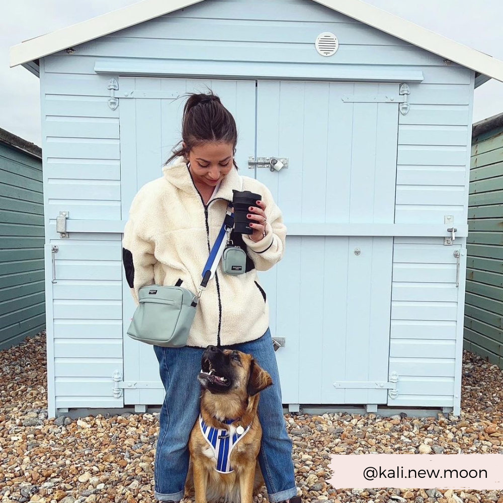 Model holding the Cocopup Black Coffee Cup whilst wearing the Cocopup Black Dog Walking Bag.